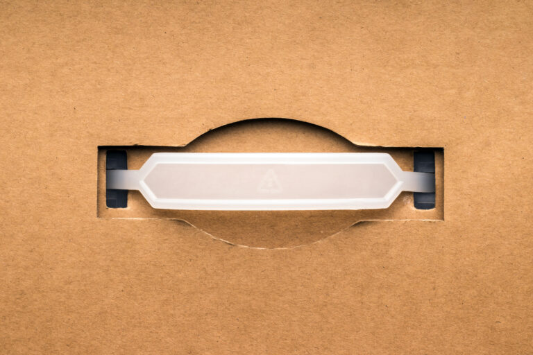 Plastic handle by cardboard box, flat lay